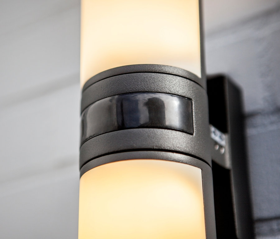 Detailaufnahme einer LED-Aussenwandleuchte mit Bewegungsmelder an einer Wand.
