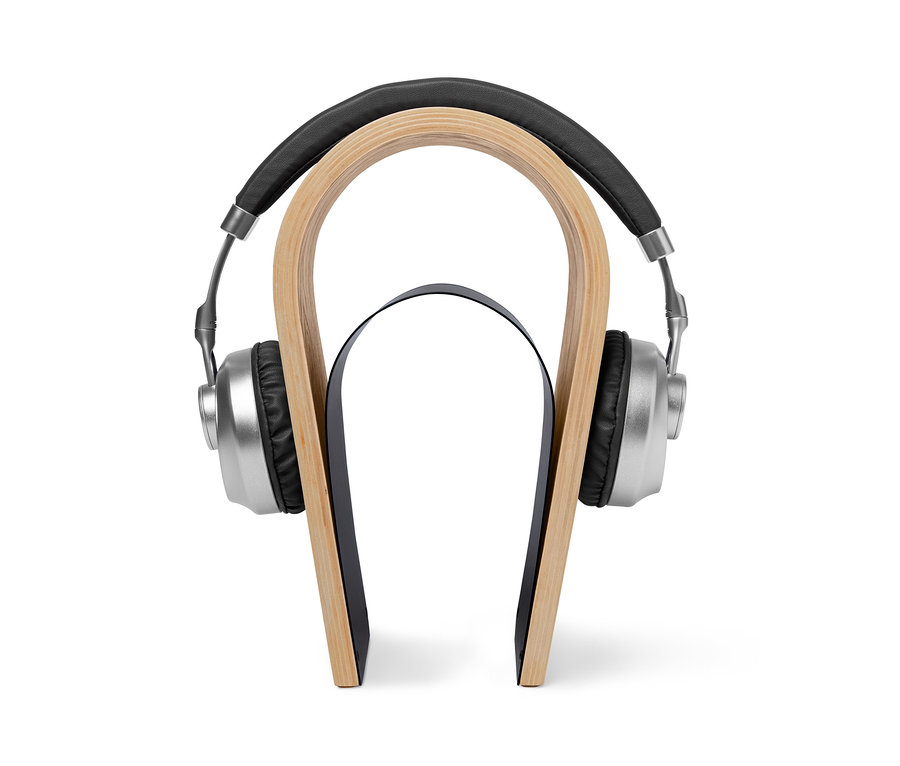 Silberfarbene Kopfhörer hängen an einem Holz-Kopfhörerständer.