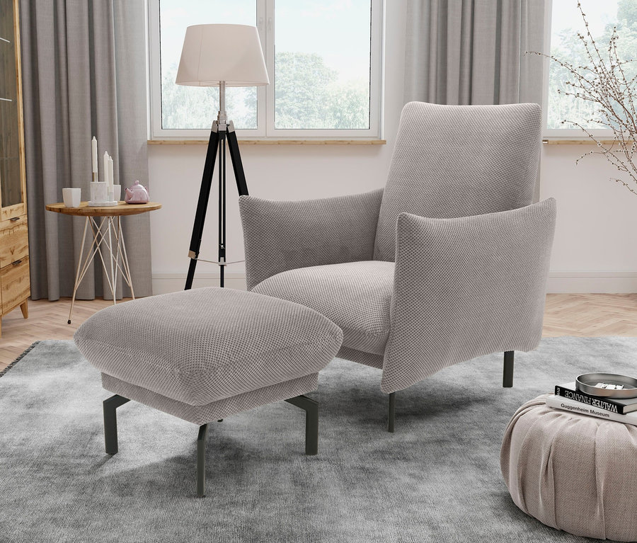 Beiger DOMO collection Sessel »Avila« mit Hocker »Avila« auf einem grauen Teppich.