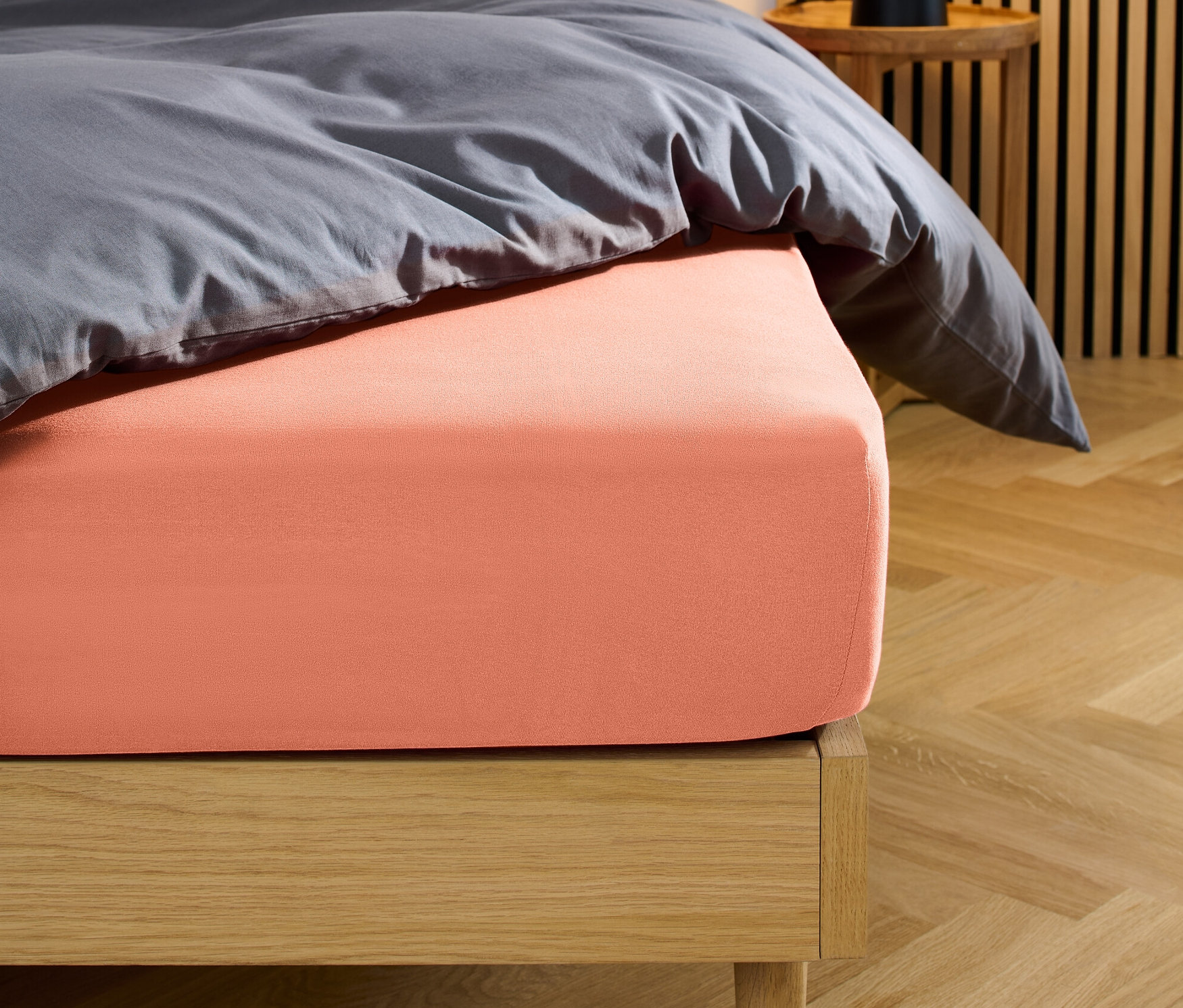 Bett mit korallenfarbenem Jersey-Spannbettlaken.