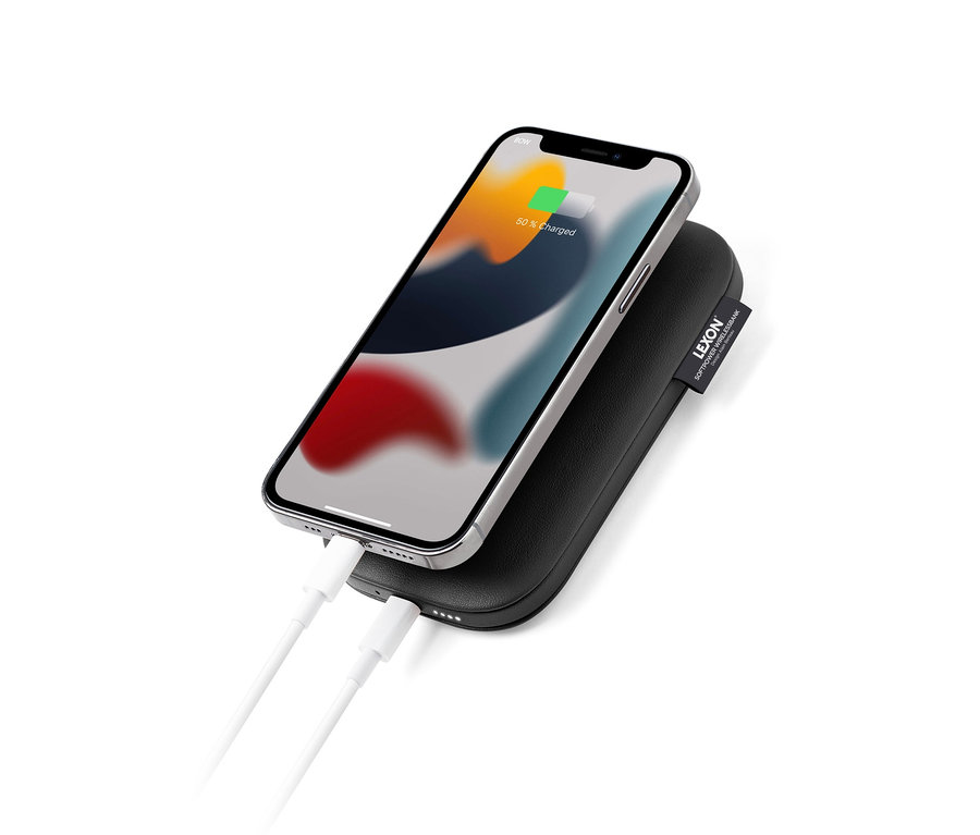 Ein Mobiltelefon wird auf einer kabellosen schwarzen Powerbank geladen. Zu sehen ist die kabellose Powerbank »SOFTPOWER« von Lexon.