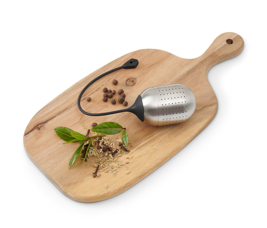 Gewürzkugel, Gewürze und Lorbeerblatt auf einem Holzbrett.