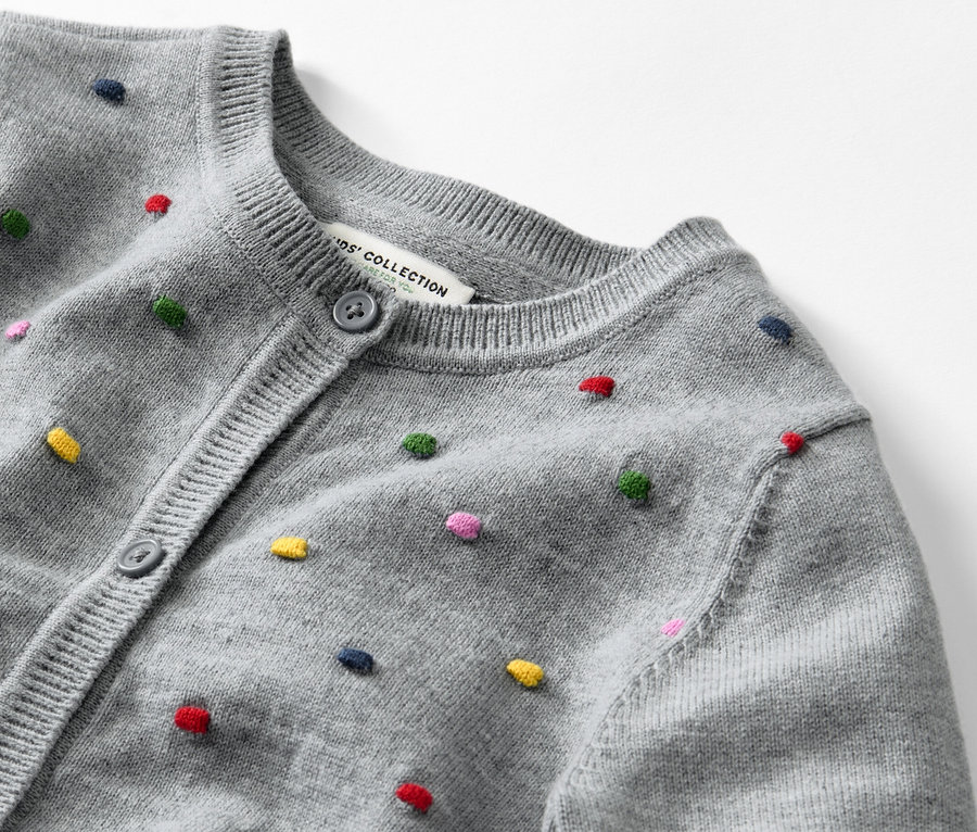 Detailansicht einer Kinder-Strickjacke mit bunten Punkten.