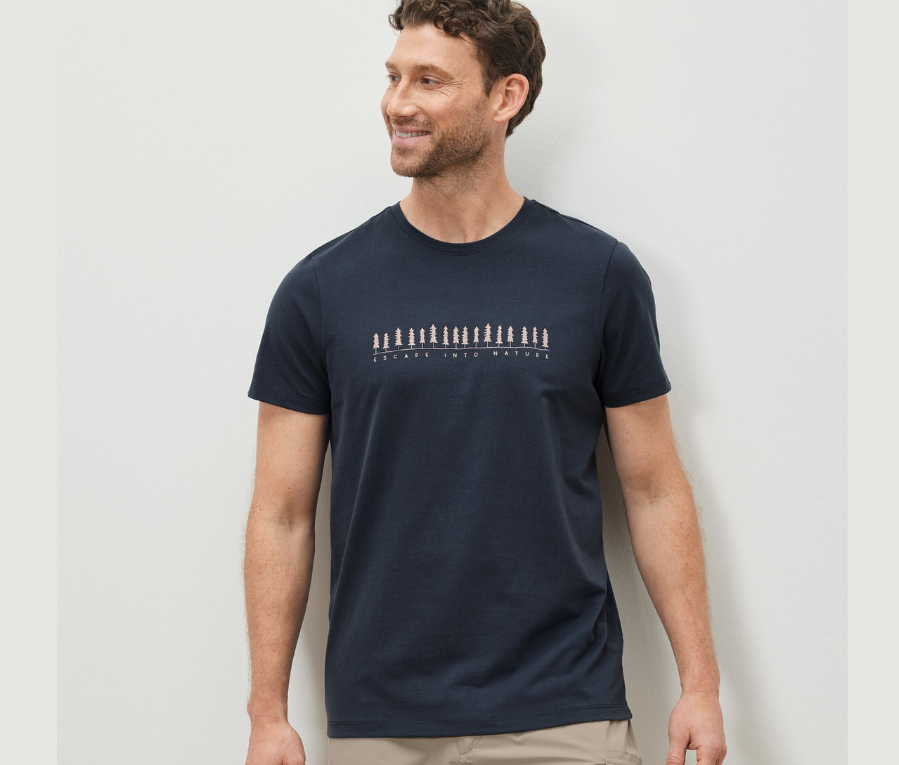 Mann mit braunen Haaren trägt ein blaues T-Shirt mit Aufdruck.