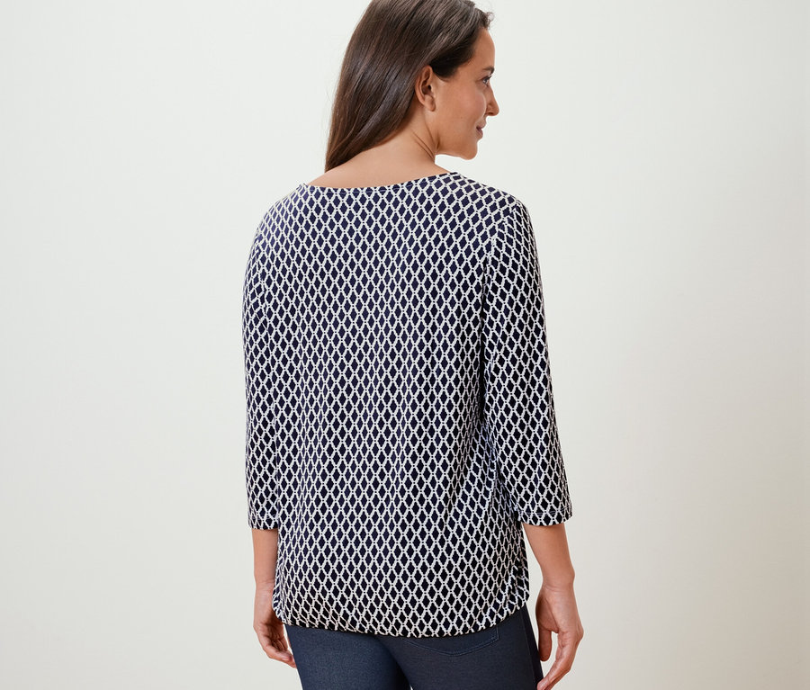 Frau trägt ein bedrucktes Blusenshirt.