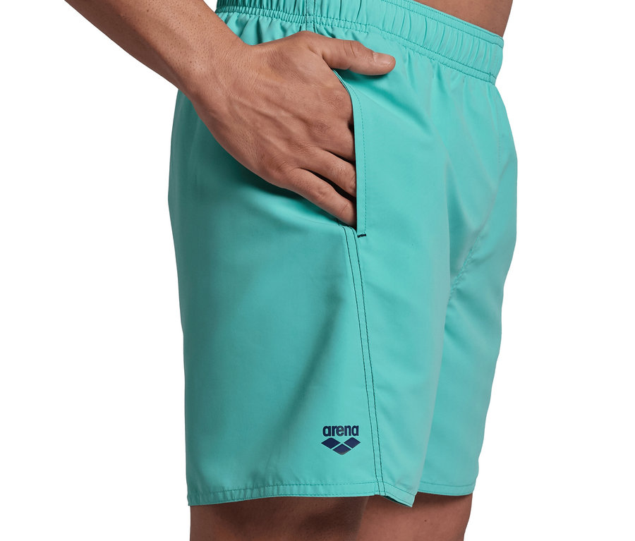 Mann hat Hand in der Tasche von hellblauen Badeshorts. arena Badeshorts Fundamentals Logo, hellblau.