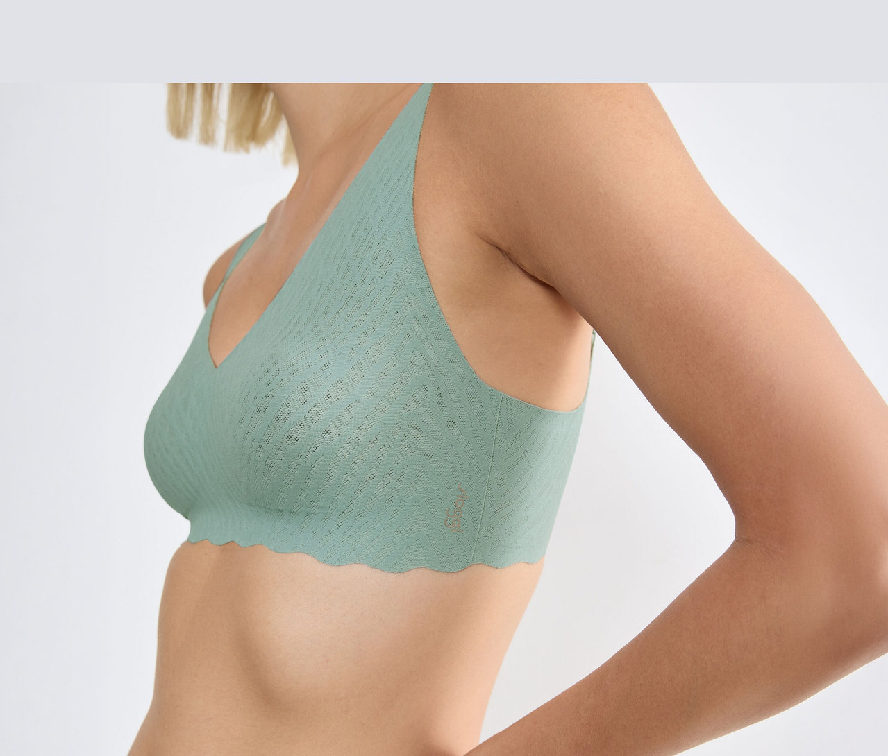 Eine Frau trägt einen sloggi ZERO Feel Bliss Soft Bra in Misty Turquoise mit gewelltem Saum und Strukturmuster.