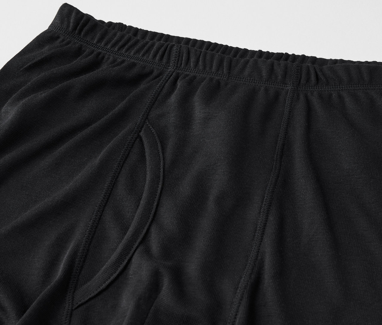 Detailansicht einer schwarzen Herrenboxershorts mit elastischem Bund und seitlichem Schlitz.