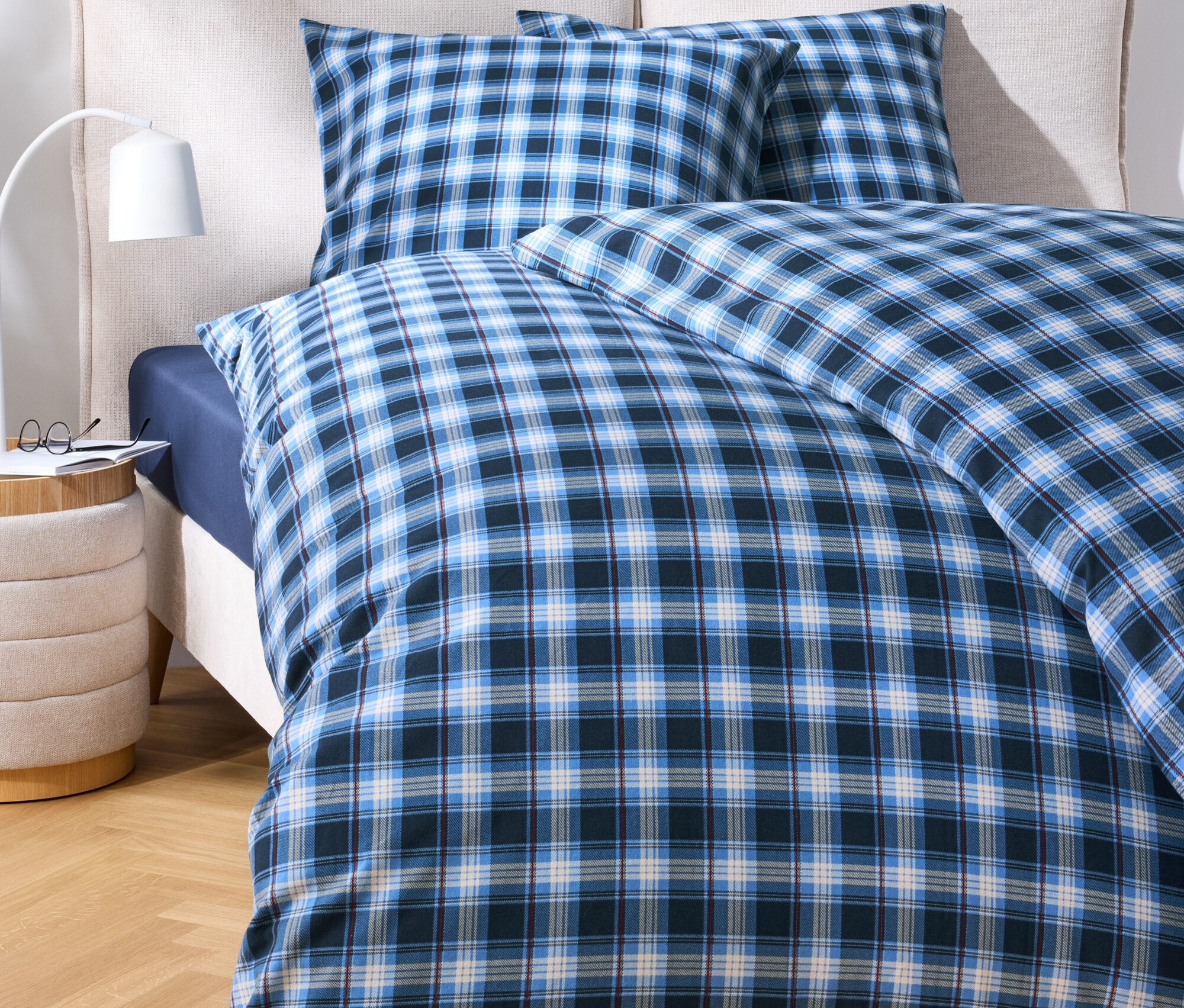 Bettwäsche mit blauem Karomuster auf einem Bett.