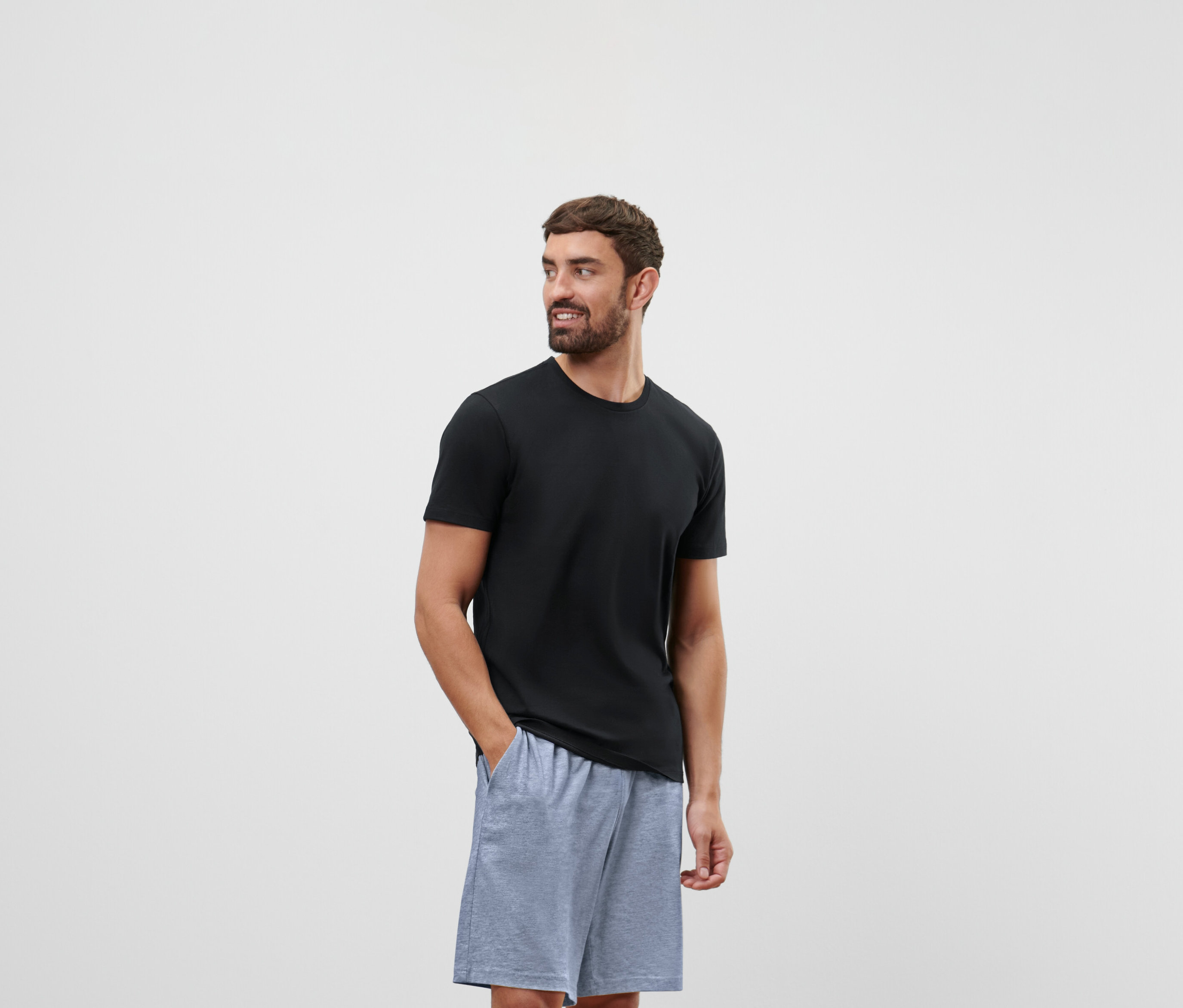 Mann in schwarzem T-Shirt und grauen Shorts blickt nach rechts.