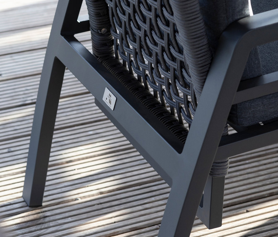 Detailaufnahme eines grauen deVries Dining-Set Stuhls mit Seilgeflecht auf einer Holzterrasse.