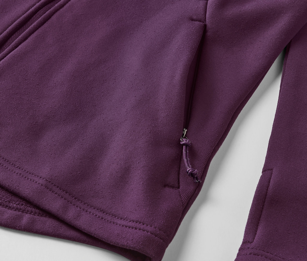 Detailaufnahme einer violetten Fleecejacke mit Reißverschluss und Tasche.