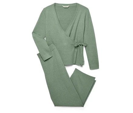 Ein grüner Strickwickelcardigan und Strickhose liegen auf einem weißen Hintergrund.