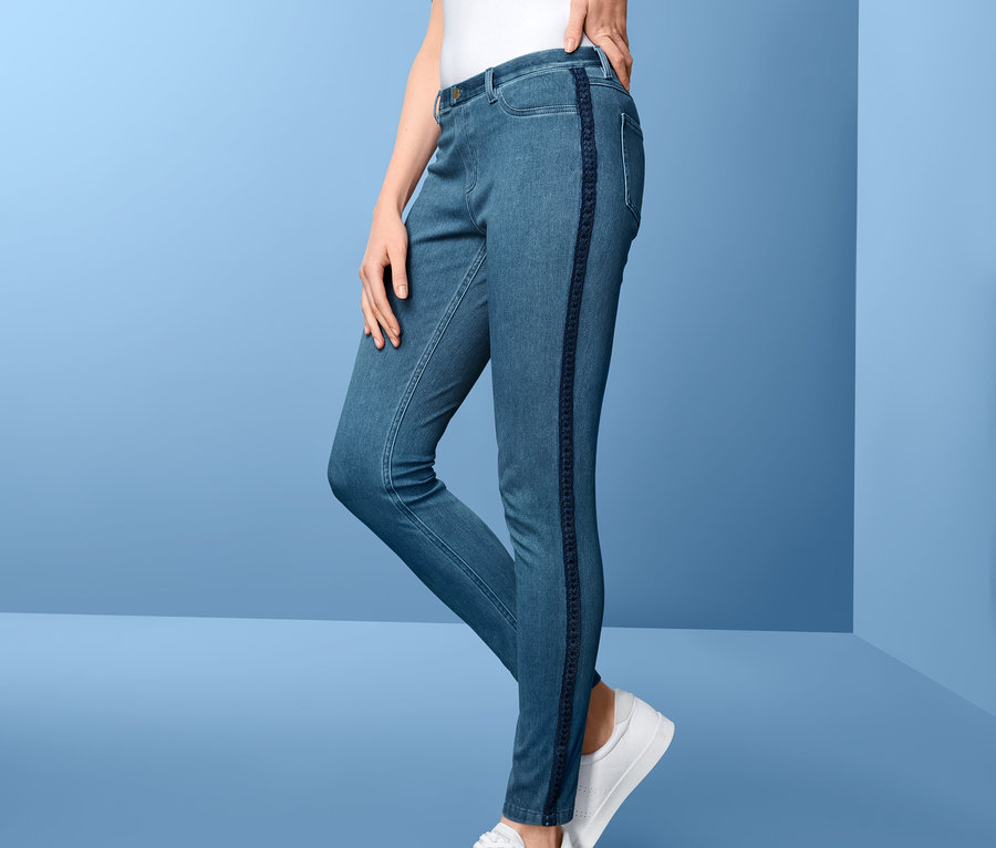 Frau posiert in Jeggings mit Seitendetails und weißen Schuhen.