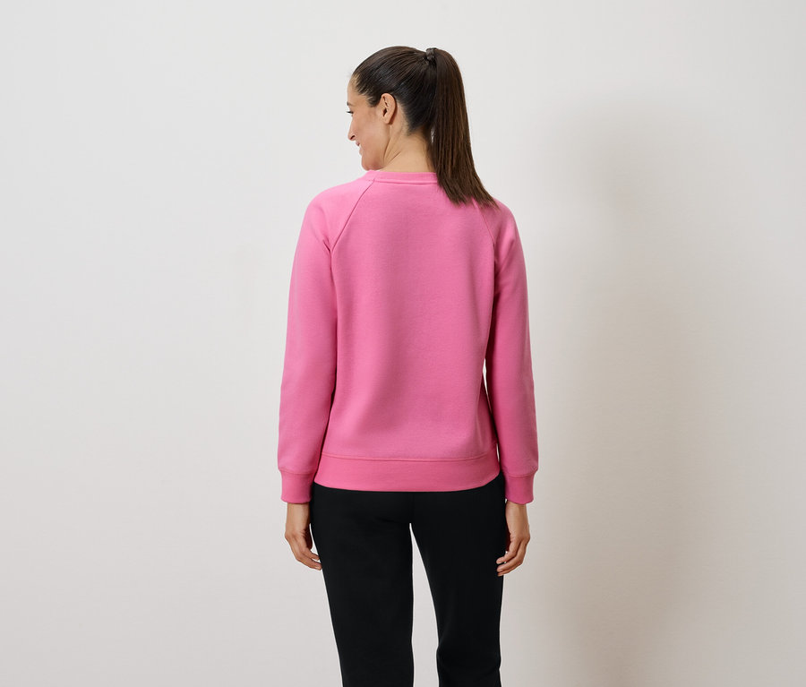 Frau mit Pferdeschwanz trägt pinkes Sweatshirt und schwarze Hose, von hinten gesehen.