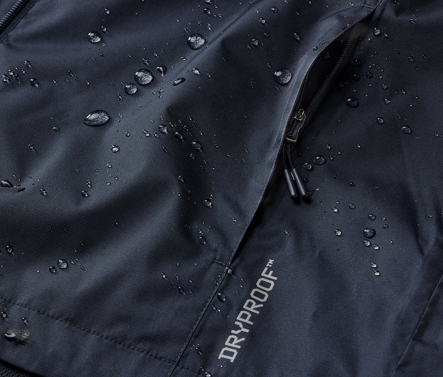 Detailaufnahme einer marineblauen Regenjacke mit Reißverschlusstasche und DRYPROOF Aufschrift.