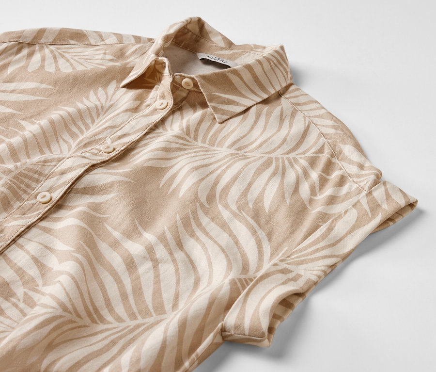 Detailansicht eines bedruckten Leinenkleids mit kurzen Ärmeln und Knöpfen.