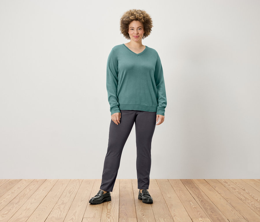 Frau posiert in einem Pullover und einer Stretchhose.