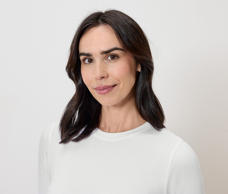 Porträt einer Frau mit dunklen Haaren in einem weißen T-Shirt.