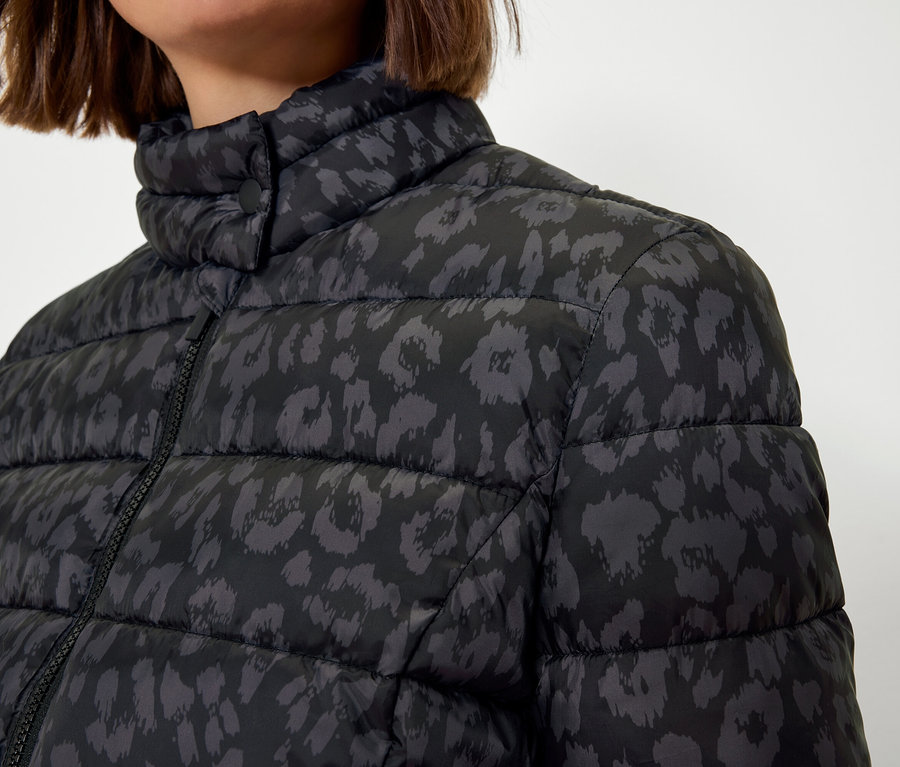 Oberkörper einer Frau in einer schwarzen Steppjacke mit Animal-Print.