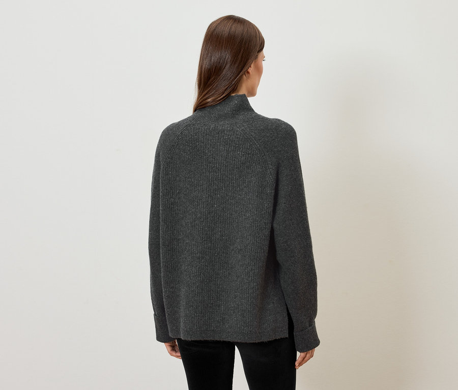 Frau mit dem Rücken zur Kamera trägt einen grauen Pullover.