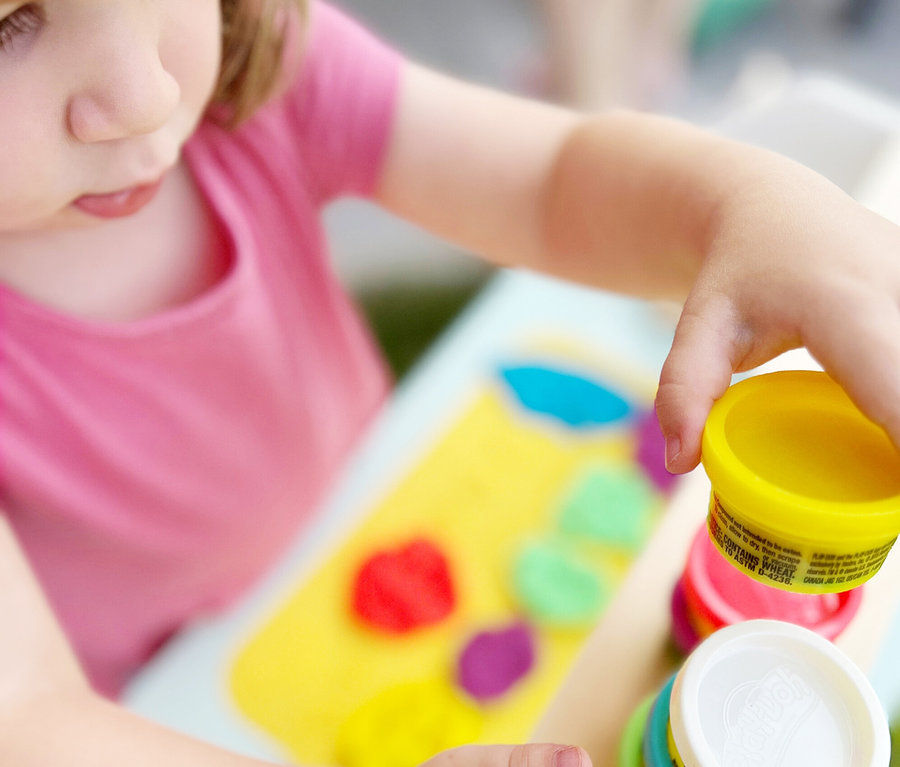 Mädchen spielt mit Knete am Tisch, inklusive roba x Play-Doh Eisstand.