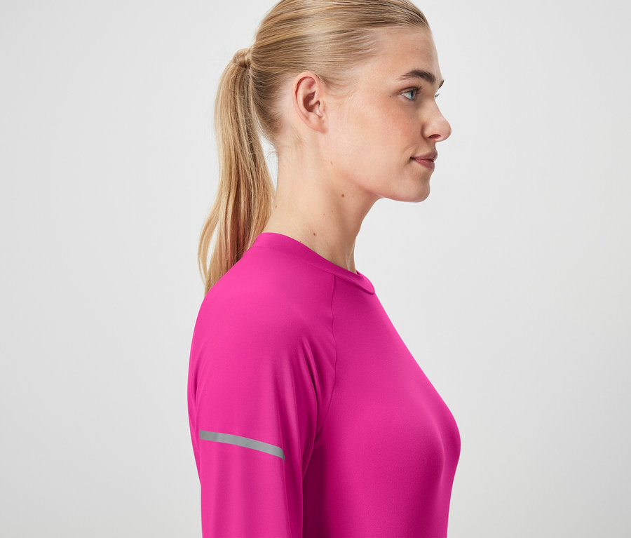 Profil einer Frau mit blonden, zum Pferdeschwanz gebundenen Haaren, die ein rosafarbenes Langarmshirt trägt.