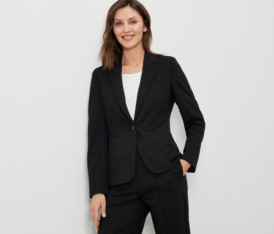 Frau trägt einen schwarzen Jerseyblazer.