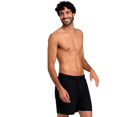 Lächelnder Mann mit lockigem Haar, der schwarze arena Evo Badeshorts trägt.