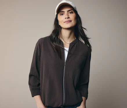 Frau mit brauner Jacke und weißer Kappe.