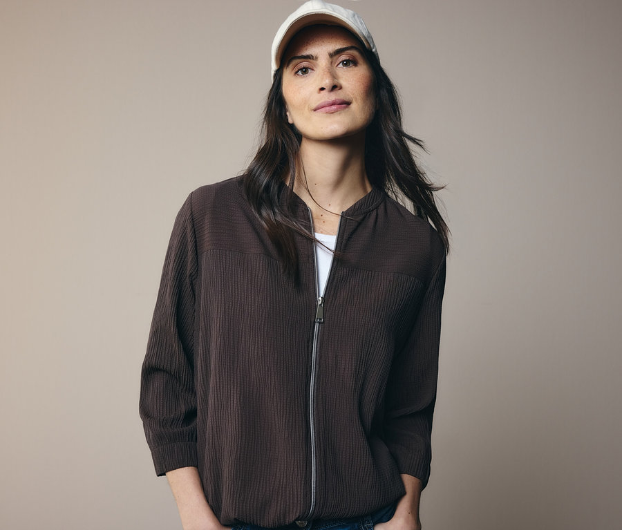 Frau mit brauner Jacke und weißer Kappe.