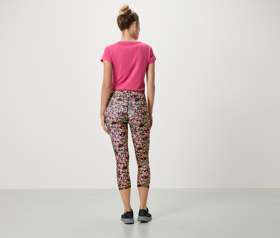 Rückansicht einer Frau mit Dutt, die ein pinkes T-Shirt und Leggings mit Blumenmuster trägt.