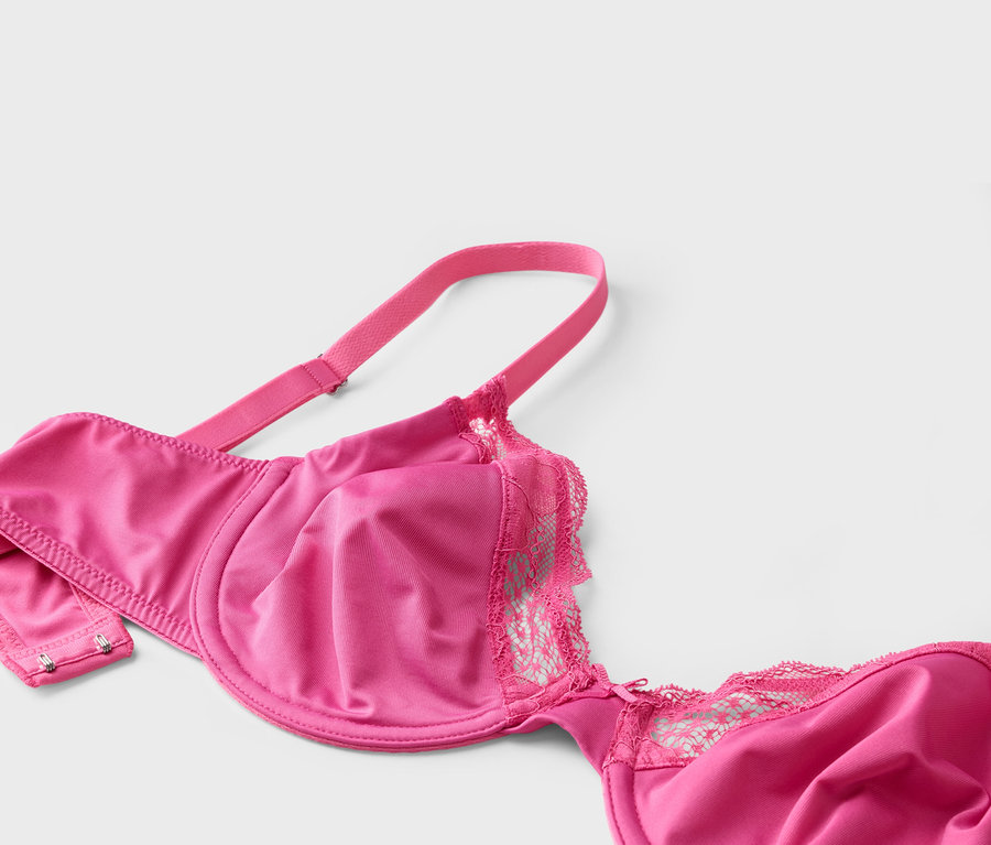 Nahaufnahme eines pinkfarbenen BHs mit Spitze auf weißem Hintergrund.