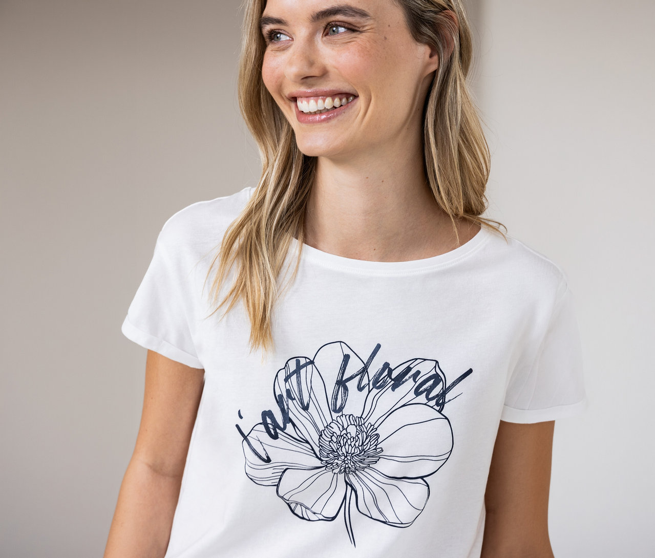 Frau lächelt und trägt ein weißes Street One T-Shirt mit Blumenmuster.
