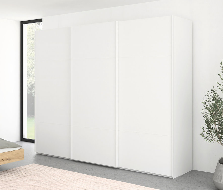 Weißer Schiebetürenschrank steht neben einem Fenster in einem Schlafzimmer.