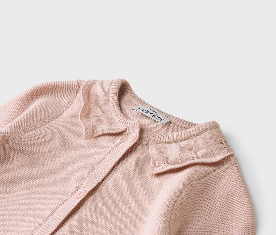 Nahaufnahme einer hellrosa Strickjacke mit Knöpfen und einem Etikett mit der Aufschrift "ICHIBO HAPPY KIDS".