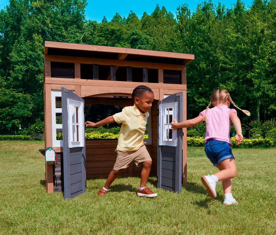 Zwei Kinder spielen vor dem Spielhaus, Trolli, auf einer Wiese.