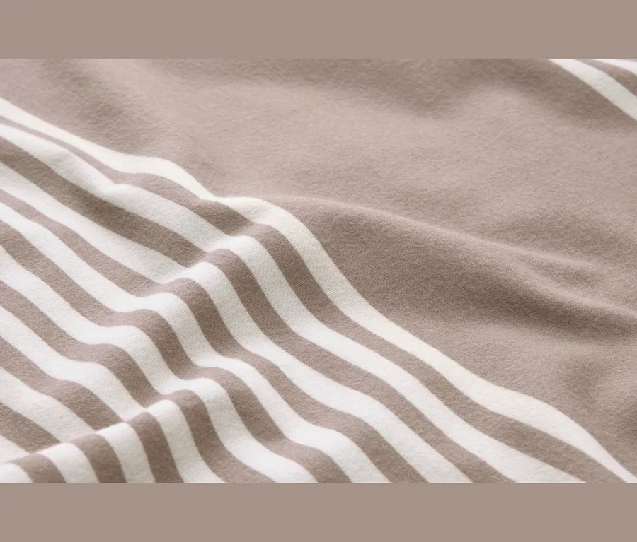 Nahaufnahme eines weichen, gestreiften Stoffes in Beige und Weiß mit Falten.