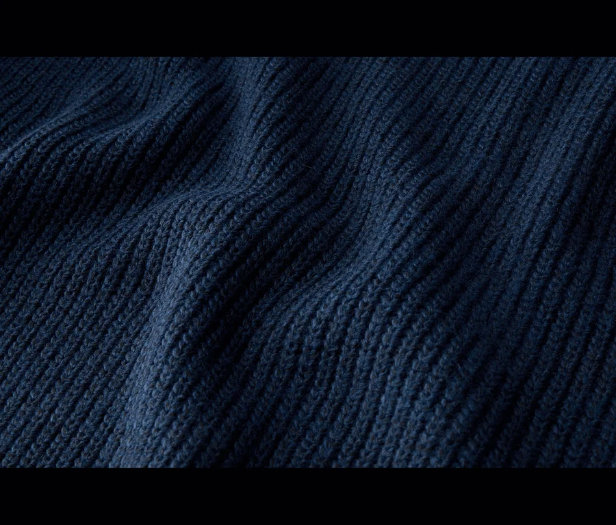 Nahaufnahme von dunkelblauem, geripptem Strickstoff mit Falten und Schatten.
