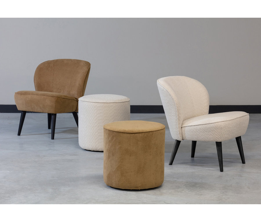 Zwei Sessel und zwei Hocker auf einem grauen Boden. Links ein brauner Sessel, rechts ein cremefarbener Sessel. Davor ein cremefarbener Bouclé-Hocker und ein gerippter brauner Hocker.