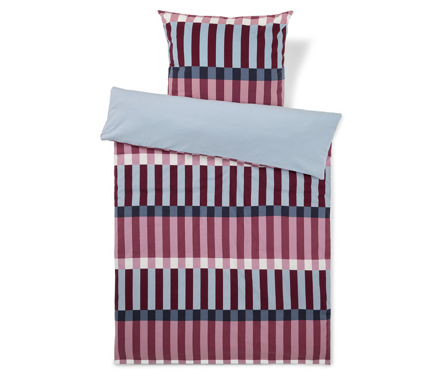 Bettwäsche-Set mit einem Kissenbezug und einem Bettbezug, die ein Muster aus vertikalen Streifen in Rosa, Hellblau, Dunkelblau und Weiß aufweisen. Ein hellblaues Laken ist über den oberen Teil des Bettbezugs gefaltet.