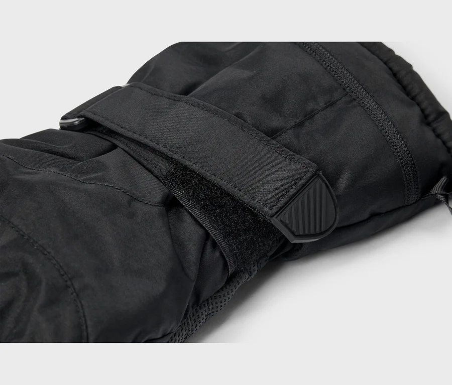 Nahaufnahme eines schwarzen Handschuhs mit verstellbarem Klettverschlussriemen am Handgelenk, der eine schwarze Gummilasche mit vertikalen Rillen aufweist.