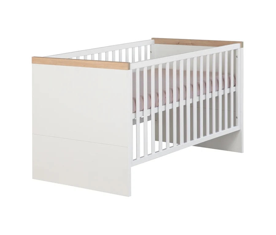 Weißes Babybett aus dem Roba Lumo 2-teiligen Kinderzimmer-Set, mit einer massiven weißen Seite und Gitterseiten, Akzenten aus Naturholz an den oberen Gitterstäben und einem rosa Laken darin.
