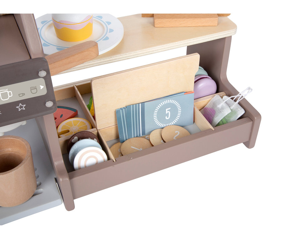 Nahaufnahme einer hölzernen Spielzeug-Kaffeemaschine mit Tasse, einem Kuchen auf einem Teller und einer Schublade voller Spielzeug-Obstscheiben, Kekse, nummerierter Karten und Netzbeutel.