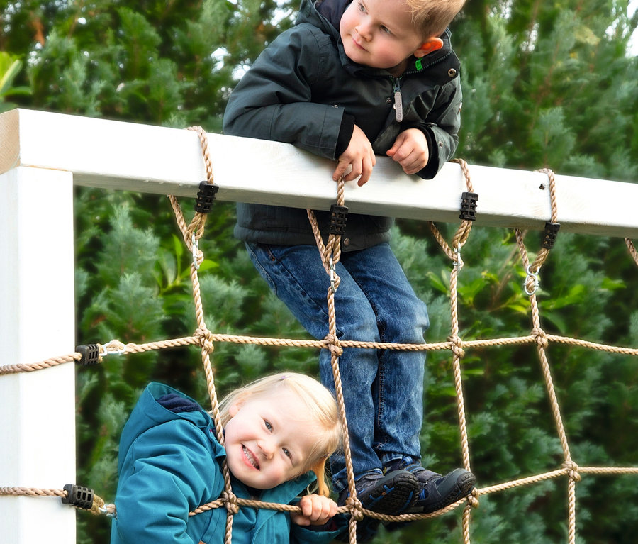 Ein Junge und ein Mädchen klettern auf einem small foot Kletternetz mit Achterhaken.
