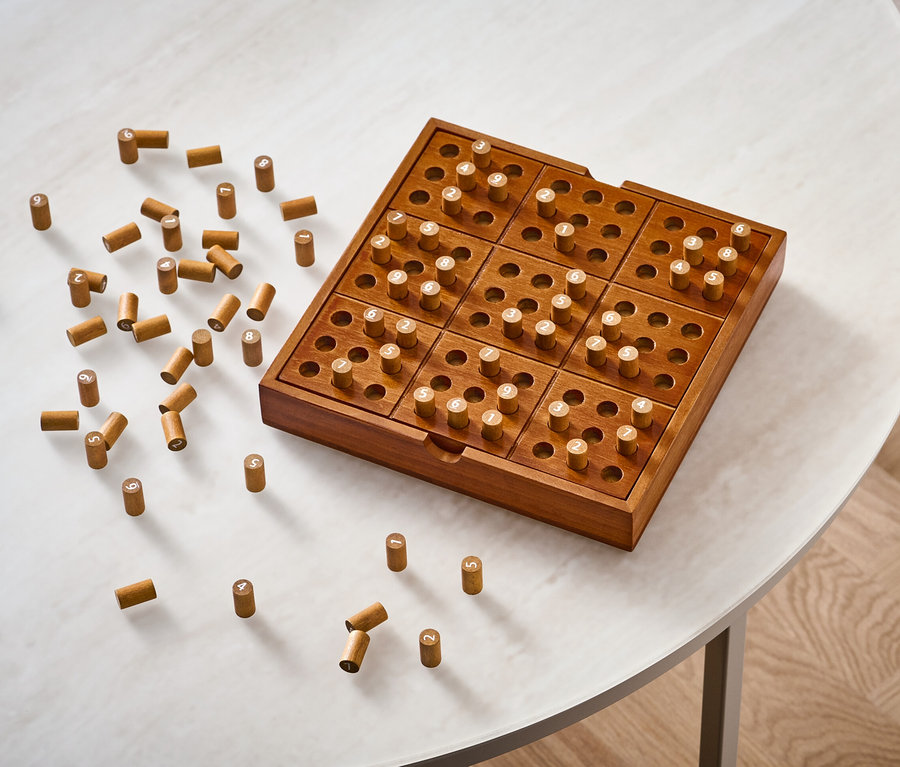 Holzbrettspiel »Sudoku« mit Stiften auf einem weißen Tisch.