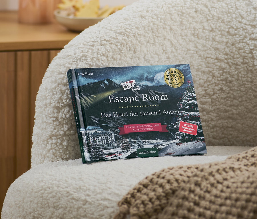 Auf einem Sessel liegen ein Escape-Room-Adventskalenderbuch »Das Hotel der tausend Augen« und eine beige Decke.