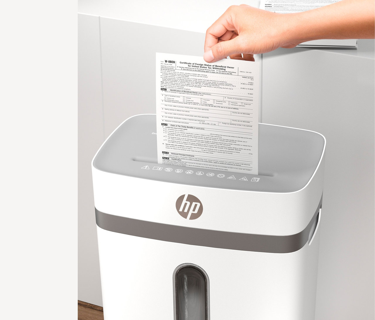 Eine Hand legt ein Dokument in einen weißen Aktenvernichter.