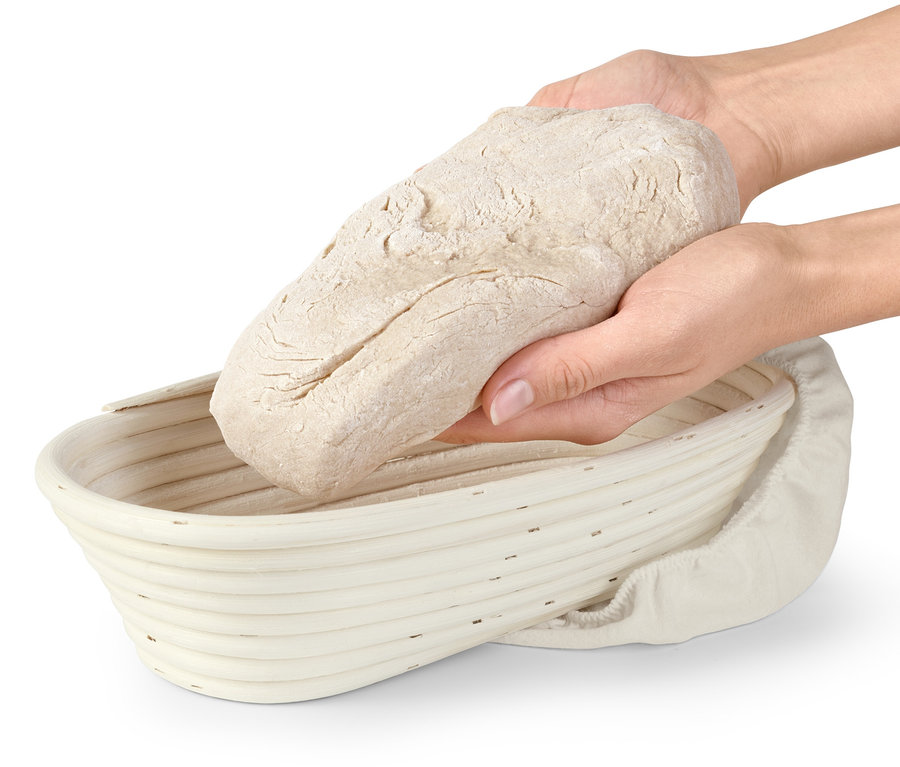 Hände legen einen Teigling in ein Gärkörbchen.