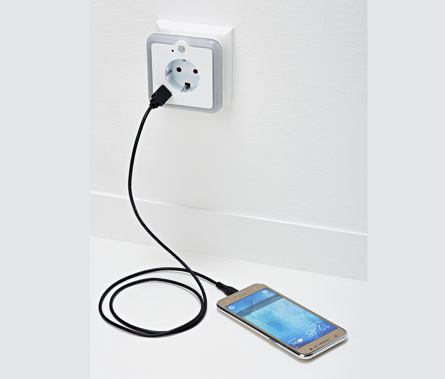 Ein Handy wird mit einem LED-Nachtlicht aufgeladen.